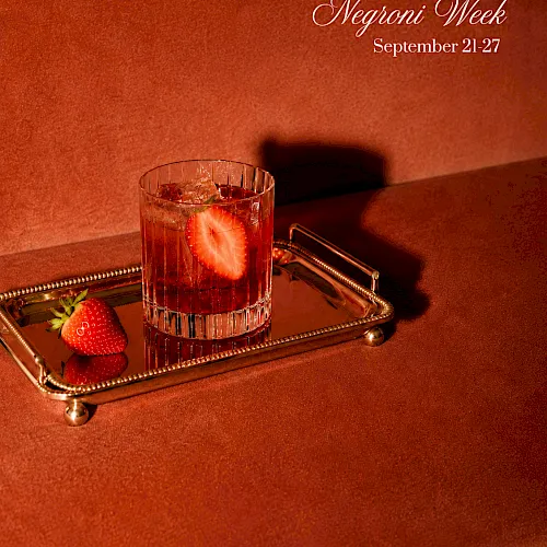 A Negroni Week promo: a pink cocktail with strawberry garnish in a glass on a gold tray, dated Sept 21&ndash;27.