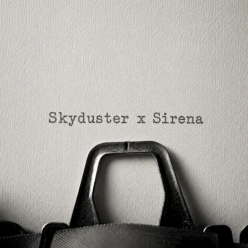 A black bag with a metal handle sits on a textured wall; over it text reads &ldquo;Skyduster x Sirena.&rdquo;