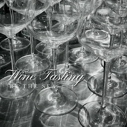 Black-and-white photo of a crowded table of wine glasses, with &ldquo;Wine Tasting by the Sea&rdquo; text overlay.