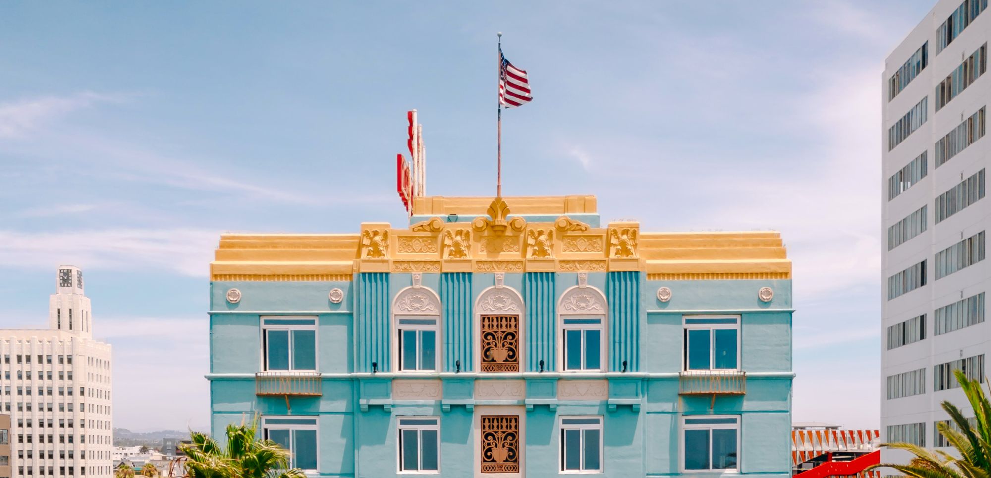 The image shows a colorful building with blue walls and a yellow roof, adorned with an American flag on top.