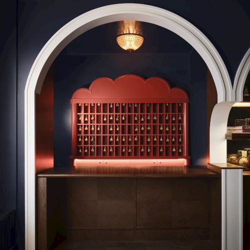 The image shows an elegant, arched alcove with a decorative bar holding numerous bottles, lit warmly, creating a cozy atmosphere.