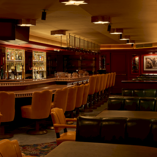 The image shows a vintage-style bar interior with leather seating, wooden bar counter, and warm lighting.