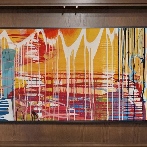 Abstract painting with colorful dripping patterns in a wooden frame setting, accompanied by a clock and decorative chess piece.