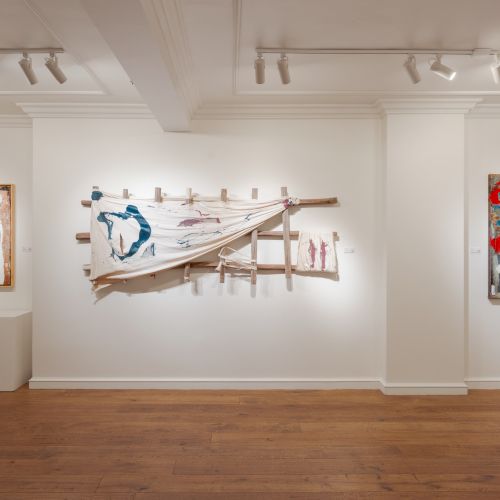 An art gallery with abstract paintings and mixed media installations on white walls, featuring bold colors and modern designs.