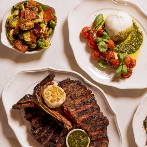 Delicious plated dishes: a grilled steak with a garlic butter and chimichurri, roasted vegetables, fresh greens, and a creamy sauce on the side.