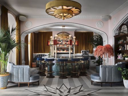 A stylish lounge with a curved bar, pastel seating, potted plants, a starburst floor pattern, warm lighting, and a vintage, retro vibe.