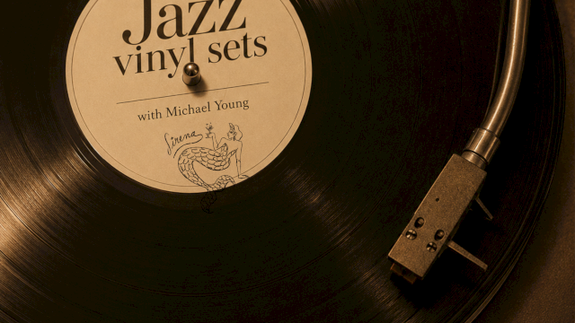 A close-up of a spinning vinyl record on a turntable, label reads &ldquo;Jazz vinyl sets,&rdquo; with text &ldquo;Sundays 5PM-9PM&rdquo; and a signature at the bottom.