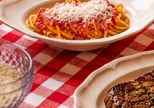 Bowl of spaghetti with red tomato sauce and grated cheese on a tablecloth, ready to serve.