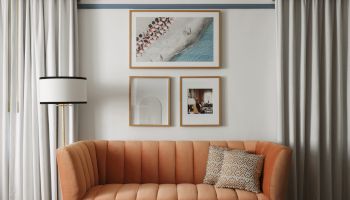 A stylish living room with a peach tufted sofa, geometric coffee table, framed wall art, striped curtains, and a modern chandelier.