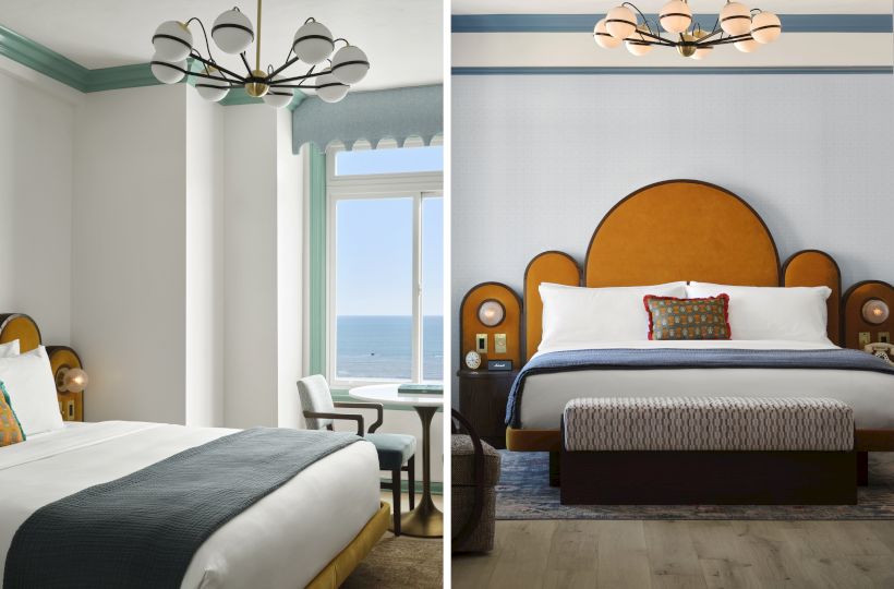 A seaside hotel suite showing two beds, arched orange headboards, teal curtains, and chandeliers above white bedding.